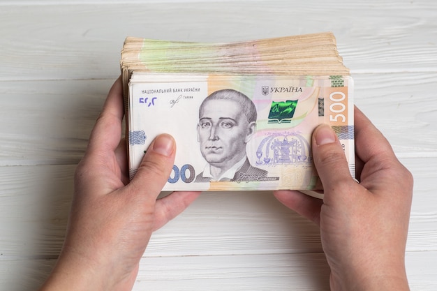 Money of Ukraine. Stack of ukrainian hryvnia banknotes in hands on wooden table. Hryvnia 500