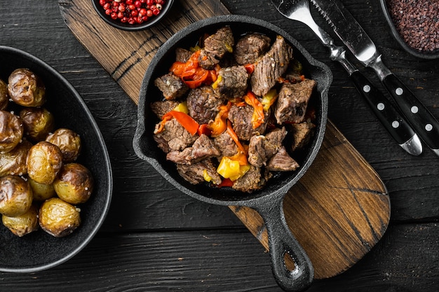 Mongolian beef, pieces of beef stewed in soy sauce set, in cast iron frying pan, on black wooden