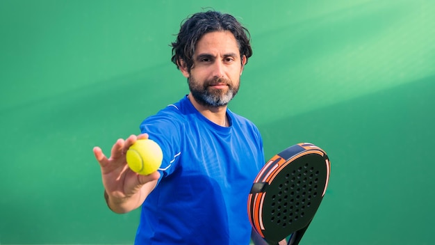 Monitor of padel holding black racket with yellow tennis ball in the hand