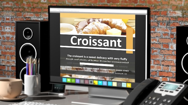 Monitor with Croissant recipe on desktop with office objects