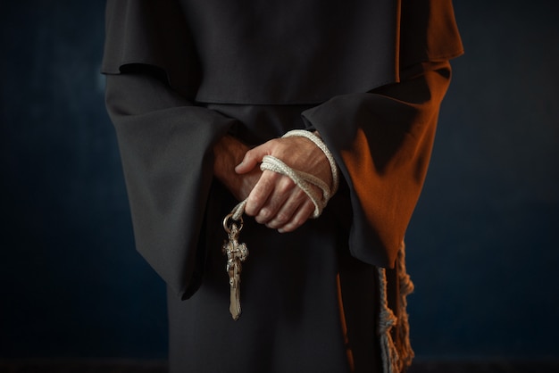 Monk holds wooden rosary and cross in hands