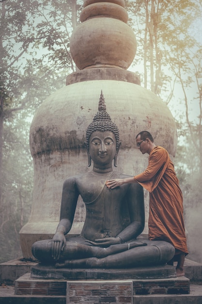 Monk scrubbing buddha statue at temple