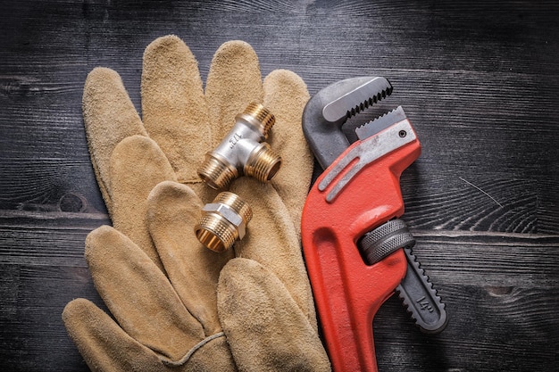 Monkey wrench plumbing fittings leather protective gloves on wooden board