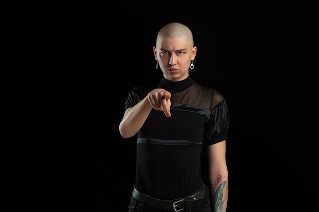 Monochrome portrait of young bald woman on black wall