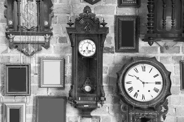 Monochrome vintage clock and picture frame hanging on an brick wall