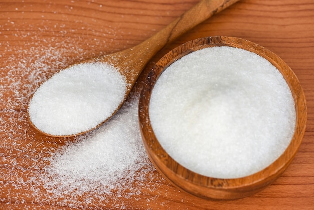 Photo monosodium glutamate on wooden bowl and spoon on the table background, msg for food seasoning