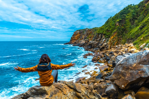 Monte Ulia in the city of San Sebastián, Basque Country. Visit the hidden cove of the city called Illurgita Senadia or Illurgita Senotia. A young girl sitting with open arms looking at the sea