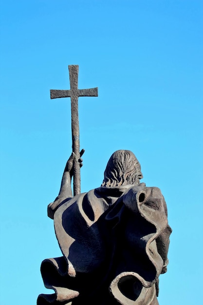 A monument of a man with a cross on sky background