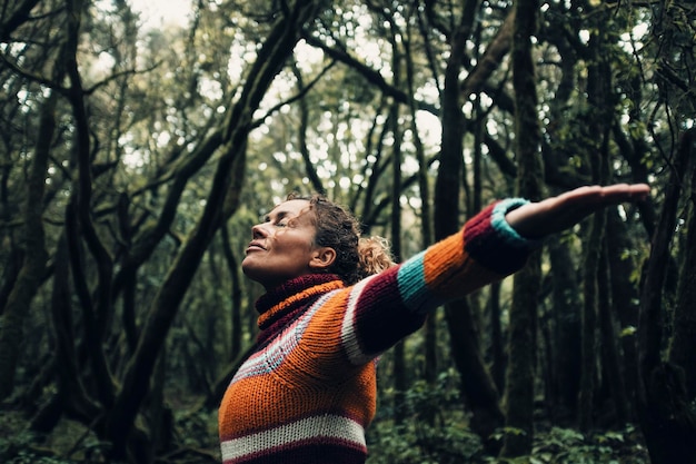 Moody color concept of people and love for nature and planet earth One person with arms up hugging forest trees around and smiling happy Environment and woman tourist concept lifestyle