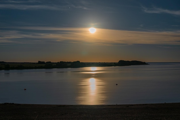 Moonrise over the river in the starry sky in light clouds. Night landscape