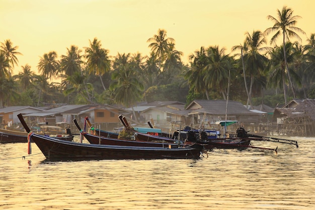 Moored fishing longtail boats with sunset sky in fishing village