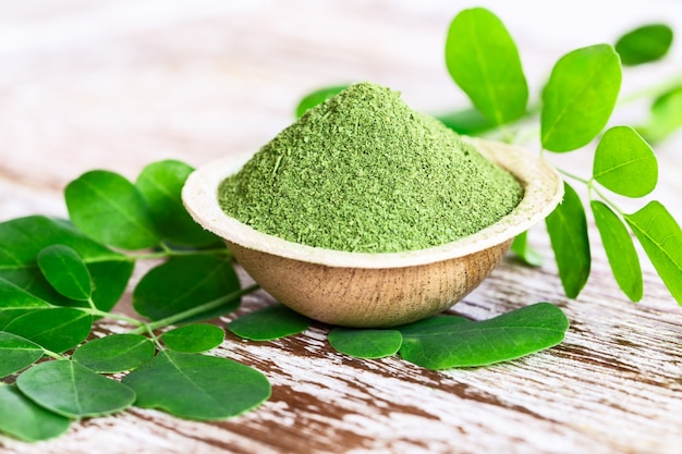 Moringa powder (Moringa Oleifera) in coconut bowl with original fresh Moringa leaves