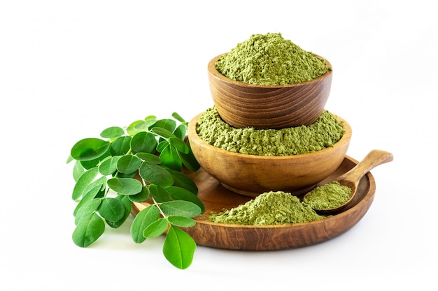  Moringa powder (Moringa Oleifera) in wooden bowl with original fresh Moringa leaves isolated on white background.