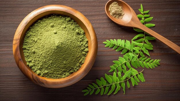 Moringa powder in wooden bowl with fresh Moringa