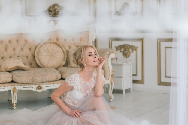 Morning of a beautiful young bride in a boudoir dress. Studio, interior.