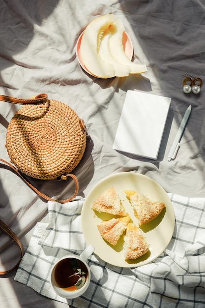 Morning breakfast in bed on blanket with tea fruit and pie wicker bag and notebook light green color