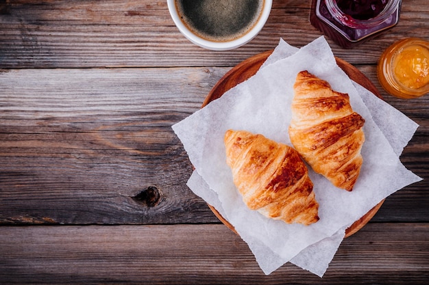 Morning breakfast Homemade baked croissants with jam and coffee on wooden rustic background Top view