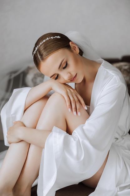 Morning of bride before the wedding Beautiful young woman with long veil in a white robe