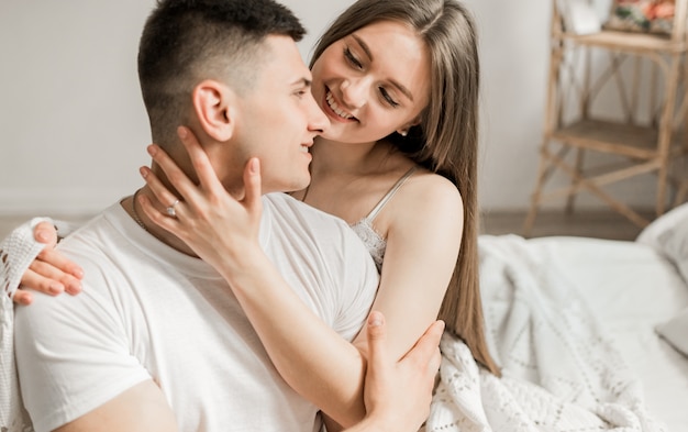 Morning of the bride and groom, lovers lie and laugh in the bedroom