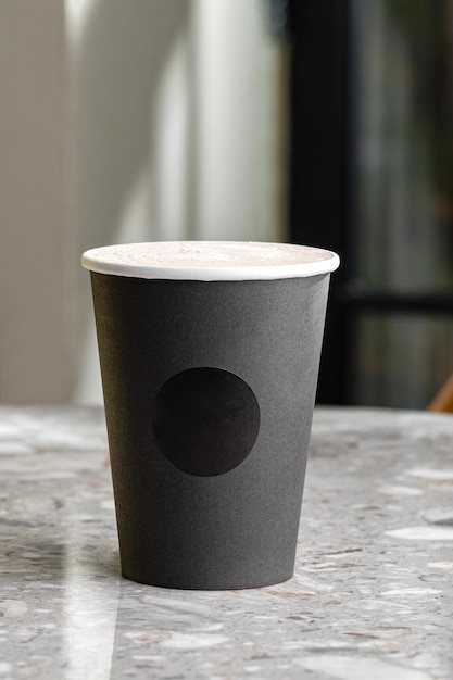 Morning coffee in black paper cup takeaway mug under light and shadown through tree