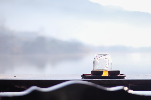 Morning cup of hot tea with lake background at sunrise