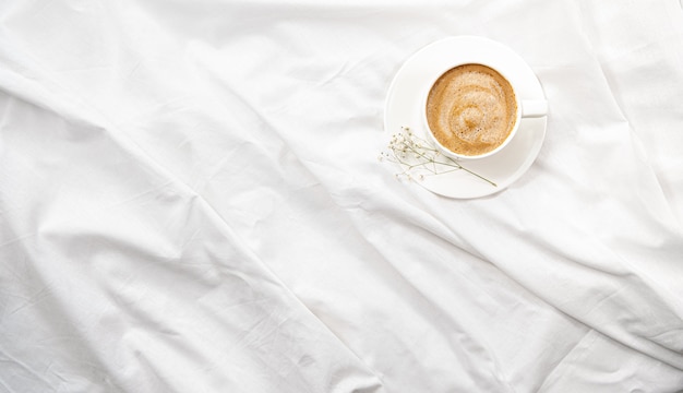 Morning flatlay in white bed. Coffee and morning routine.