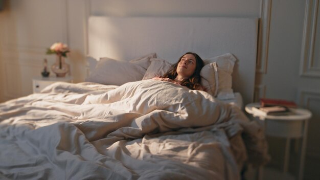 Morning girl stretching bed in sunlight peaceful positive model waking up early