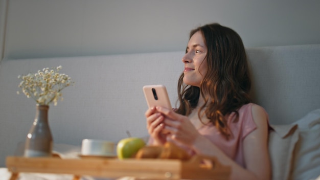 Morning girl using smartphone at home closeup smiling serene woman dreaming