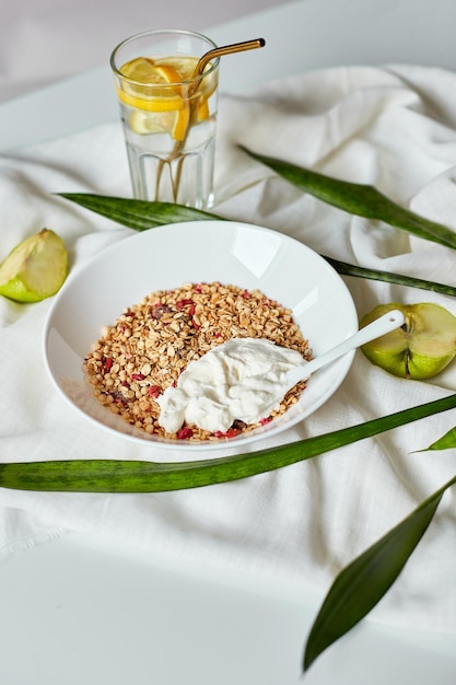 Morning granola breakfast with greek yougurt and glass of detox water