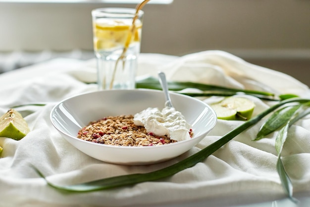 Morning granola breakfast with greek yougurt and glass of detox water