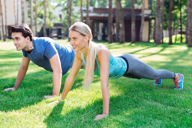 Morning gymnastics. Positive healthy couple doing exercises while having a workout in the morning