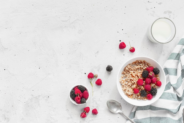 Morning healthy breakfast, white bowl full with granola, muesli, raspberry, blackberry on gray concrete table. Healthy eating, eco, bio food concept. Fresh tasty meal on grey background. Quality photo