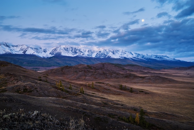 Morning in the Kurai steppe, the Moon over the North Chuysky ridge. Kosh-Agachsky District, Altai Republic, Russia