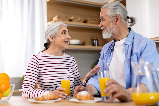 Morning Meal Happy Senior Spouses Eating Breakfast And Chatting In Kitchen