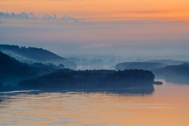 Morning mystic haze above broad valley of river. Gold glow from dawn in sky. 