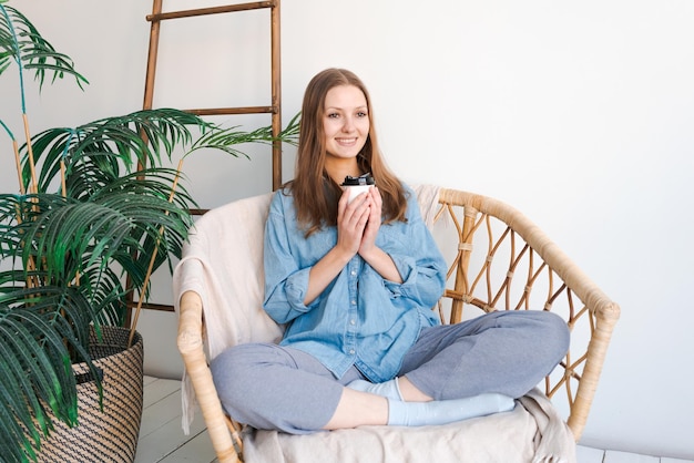 Morning relaxation Girl sits in wicker chair and enjoys coffee in cozy home