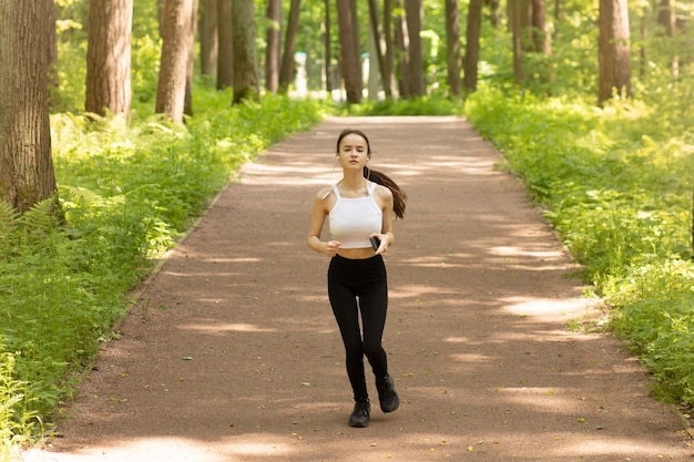 Morning run in the park Young girl in headphones goes in for sports