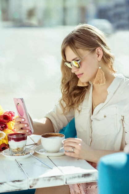 Morning. Smiling girl with the phone, cup of coffee and yogurt