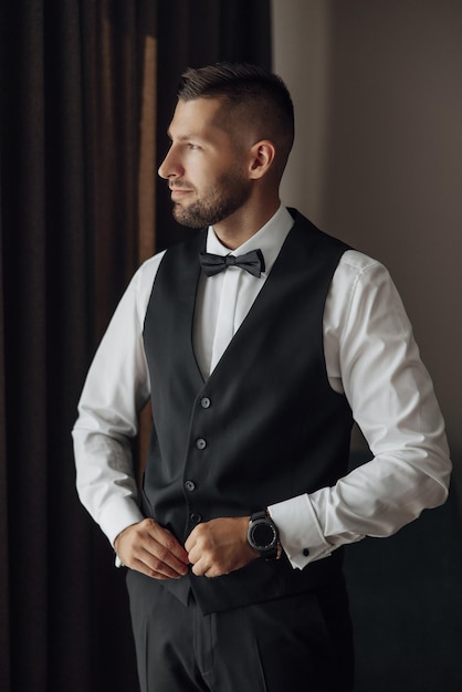 Morning of a stylish groom man in a black suit and tie his preparations at the hotel