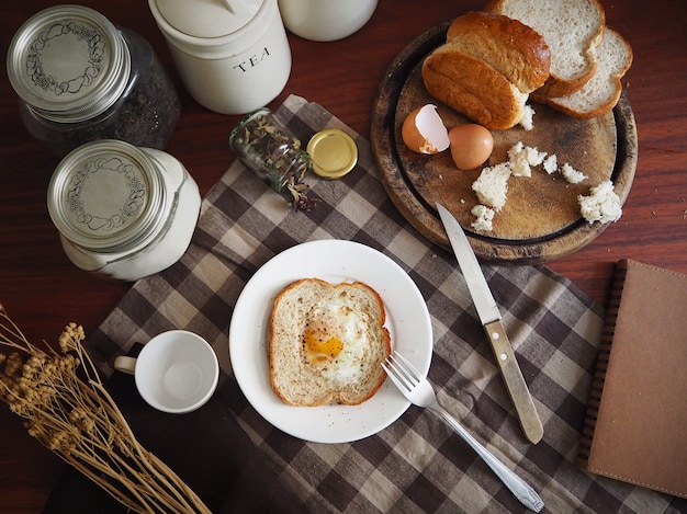 morning table breakfast of bread and egg with a cup of tea on brown checkered tablecloth