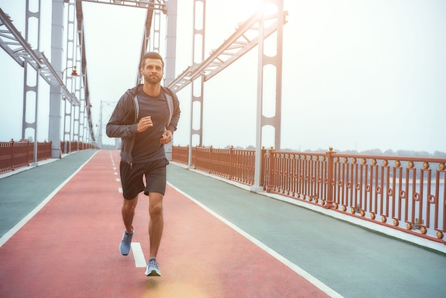 Morning workout full length of young and healthy man in sports clothing jogging on the