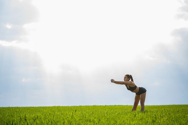 Morning workout. Healthy lifestyle concept. Young attractive woman in sportswear makes stretching her hand before training on the nature at dawn. Muscle warming