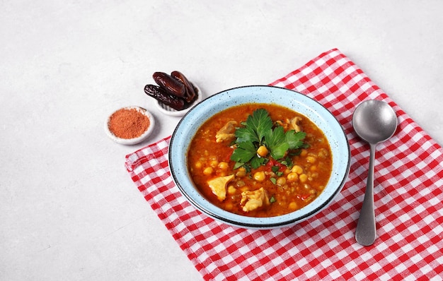 Moroccan harira soup in blue bowl at grey concrete table top and red napkin harira is moroccan cuisi