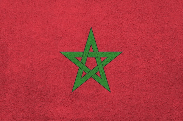 Morocco flag depicted in bright paint colors on old relief plastering wall.