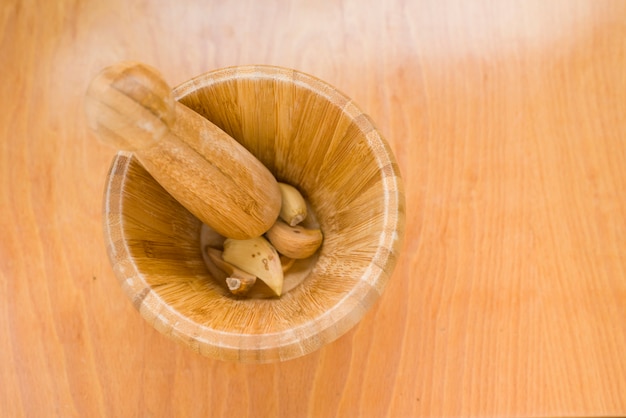 Mortar with dried garlics about to be crushed in horizontal photo on wooden background