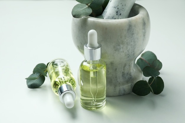 Mortar with eucalyptus and dropper bottles of oil on white background