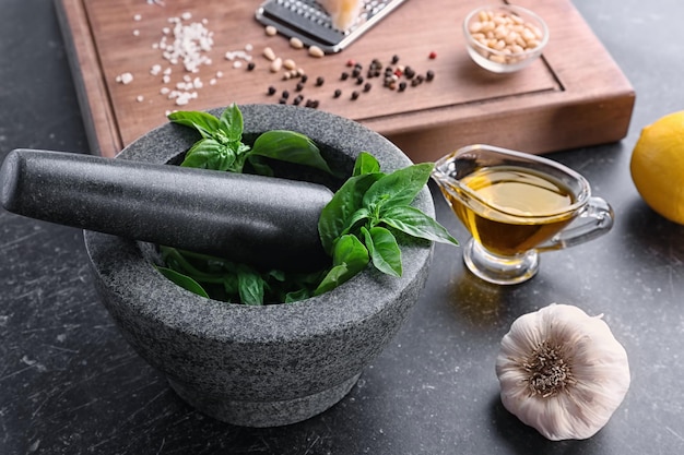 Mortar with pestle and basil leaves on table