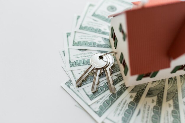 Photo mortgage, investment, real estate and property concept - close up of home model, dollar money and house keys