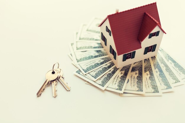 Photo mortgage, investment, real estate and property concept - close up of home model, dollar money and house keys