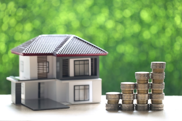 Mortgage,Model house and stack of coins money on natural green background,Business investment and real estate concept